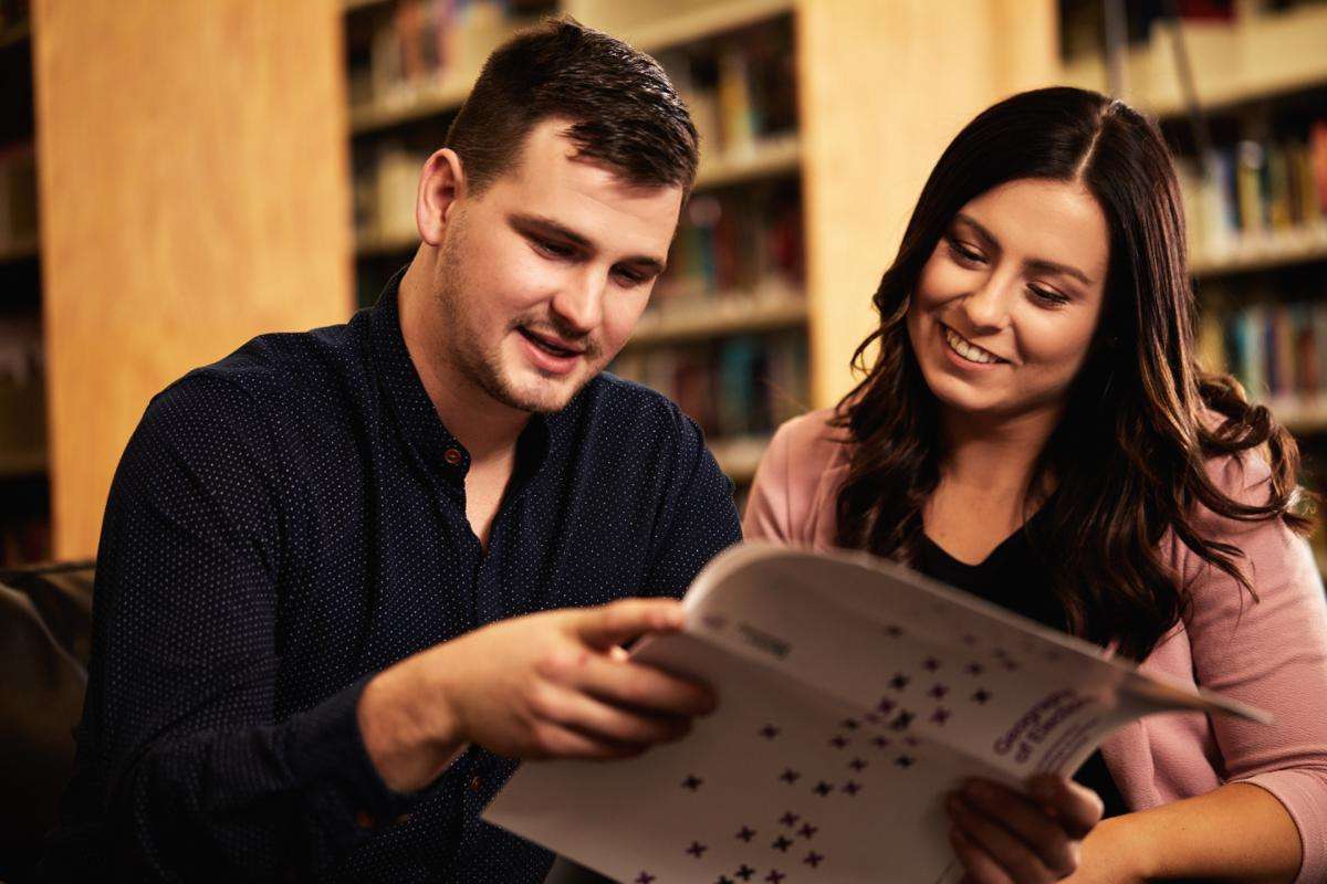 two people on couch looking at resource two people on couch looking at resource