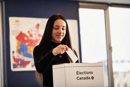 Une élève dépose un bulletin de vote dans une urne