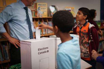 Un étudiant insère un bulletin de vote dans une urne.