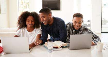 Un parent et ses enfants travaillent à l'ordinateur.