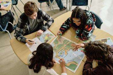 Dans une salle de classe, un groupe d'élèves travaille ensemble sur une activité d'apprentissage. Des cartes plastifiées sont placés sur la table. 