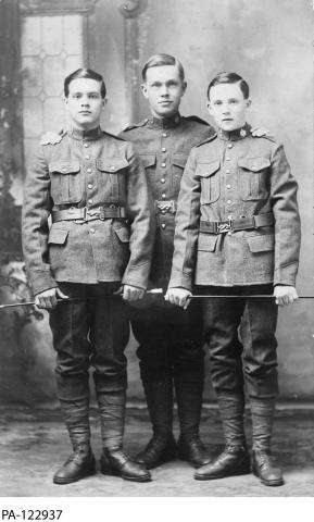 Photographie en noir et blanc de trois jeunes soldats en uniforme.