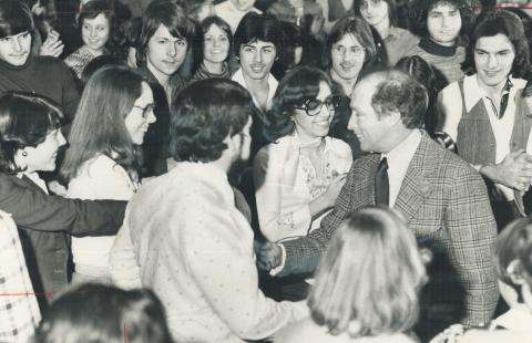 CE08-Youth-L_FR Photographie en noir et blanc du premier ministre Pierre Trudeau serrant la main d’une jeune personne, au milieu d’une foule de jeunes souriants.