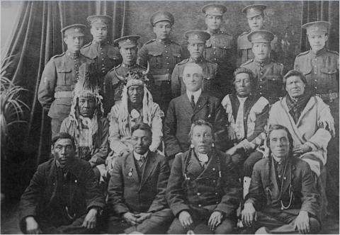Photographie en noir et blanc des Forces canadiennes qui accueillent pour la première fois dans leurs rangs des soldats autochtones. Les deux rangées du bas comprennent des soldats autochtones dans leur habit traditionnel; les deux rangées du haut comprennent des soldats debout en uniforme.