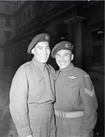 Photographie en noir et blanc du sergent Tommy Prince (à droite), 1er bataillon de parachutistes canadiens, en compagnie de son frère, le soldat Morris Prince (à gauche), à une cérémonie d’investiture au Palais de Buckingham.