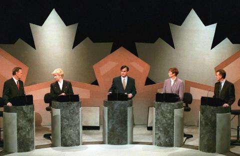 Photo d’un débat des chefs diffusé à la télévision pendant l’élection fédérale de 1993. Cinq politiciens sont debout chacun à une tribune. Deux grandes feuilles d’érable se trouvent en arrière-plan.