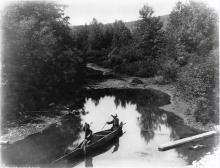 VRTT_FNP_tempsimmemoriaux Image en noir et blanc de deux hommes autochtones dans un canot d’écorce à Restigouche, au Québec.