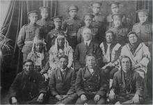 VRTT_FNP_1917_FR Photographie en noir et blanc des Forces canadiennes qui accueillent pour la première fois dans leurs rangs des soldats autochtones. Les deux rangées du bas comprennent des soldats autochtones dans leur habit traditionnel; les deux rangées du haut comprennent des soldats debout en uniforme.